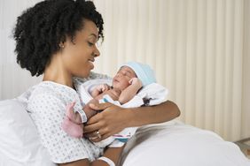 Smiling mother holding newborn baby in hospital