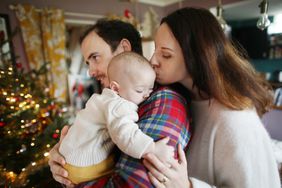 A 6 months old baby in the arms of his parents at home, in a Christmas atmosphere