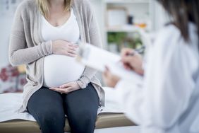 pregnant person sitting on a dcotor's table