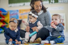 Three babies sitting with teacher a daycare