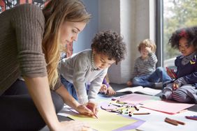 Teacher drawing with students on floor at preschool