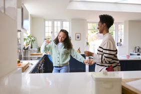 Mother With Teenage Daughter Having Fun Dancing In Kitchen At Home Together