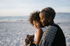 A mother and her daughter cuddling and laughing at the beach