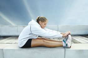 lady stretching her legs and listening to music