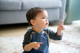 Baby boy in overalls pointing. 