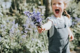 little girl in a field holding bluebell flowers