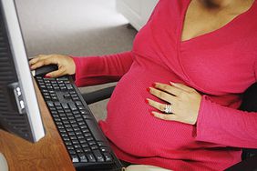 pregnant woman typing on computer