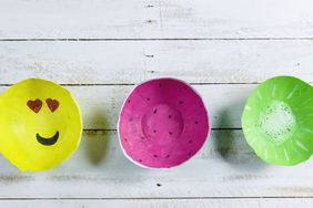 Three paper mache bowls in yellow, pink, and green on a white wooden table