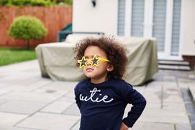 Toddler girl wearing star shaped yellow sunglasses in the garden