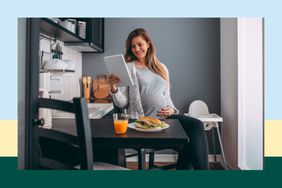 Pregnant woman looking at tablet before while eating lunch 