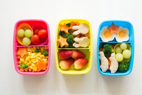 Three colorful lunchboxes with different cutout snacks 