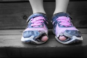 Worn out old shoes with holes in the toes used by a homeless child