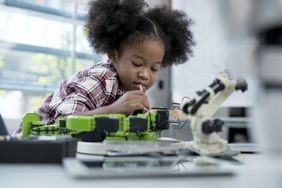 Young Black girl assembling a robot in a technology class.