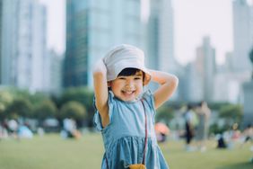 Portrait of happy little Asian girl having fun playing in urban park, smiling joyfully. 