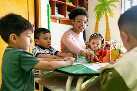 Teacher supervises a group of preschoolers coloring in class.