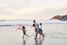 Family playing running and playing on beach at sunset 