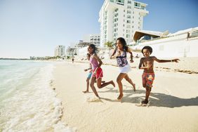 Wide shot of siblings running into ocean while on family vacation