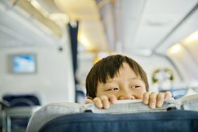 Kid boy looking over seat in an airplane when traveling