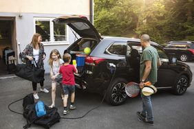 Family loading electric car for vacation. 