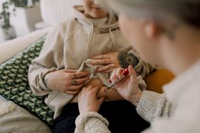 A person giving their partner an IVF shot in their stomach.