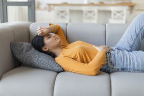 women laying with pained expression, holding stomach