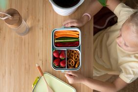 A blonde child sits in front of an open lunchbox 