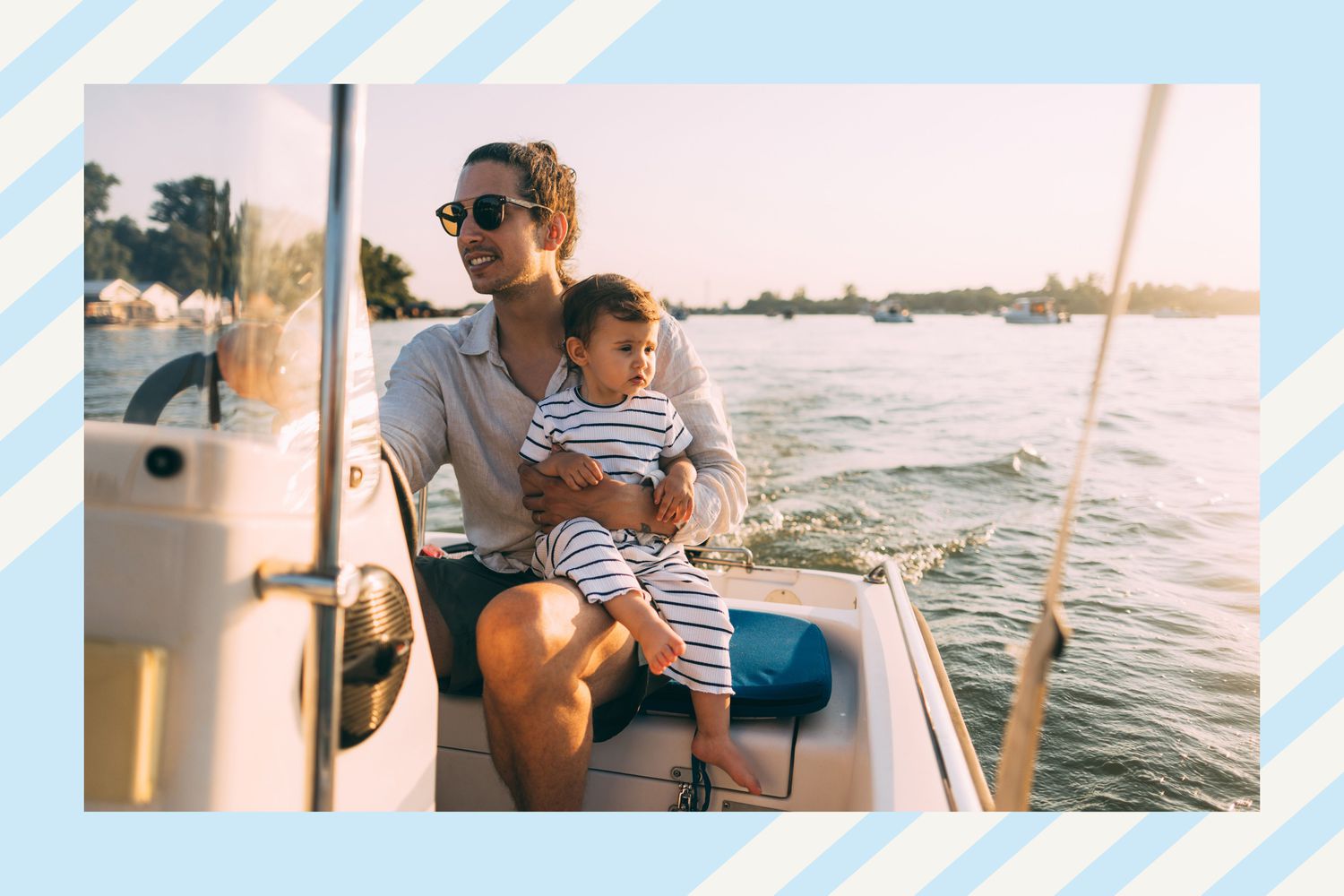 A man driving a boat at sunset with his toddler son on his lap