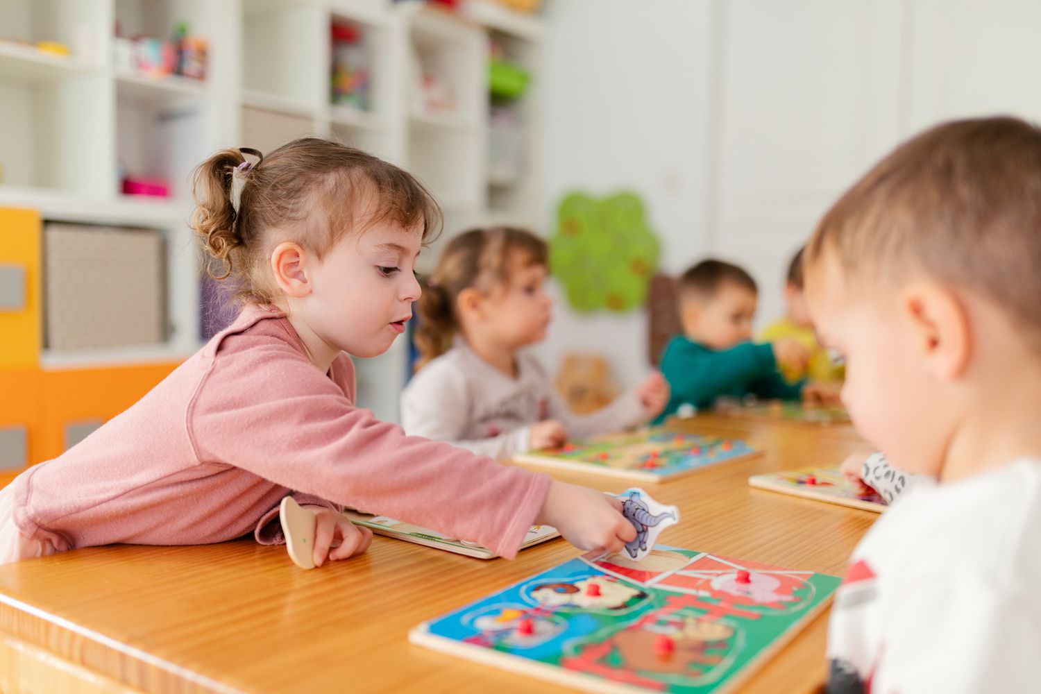 A group of children playing with puzzles on the table at preschool 