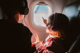 Young girl points out of a window on an airplane