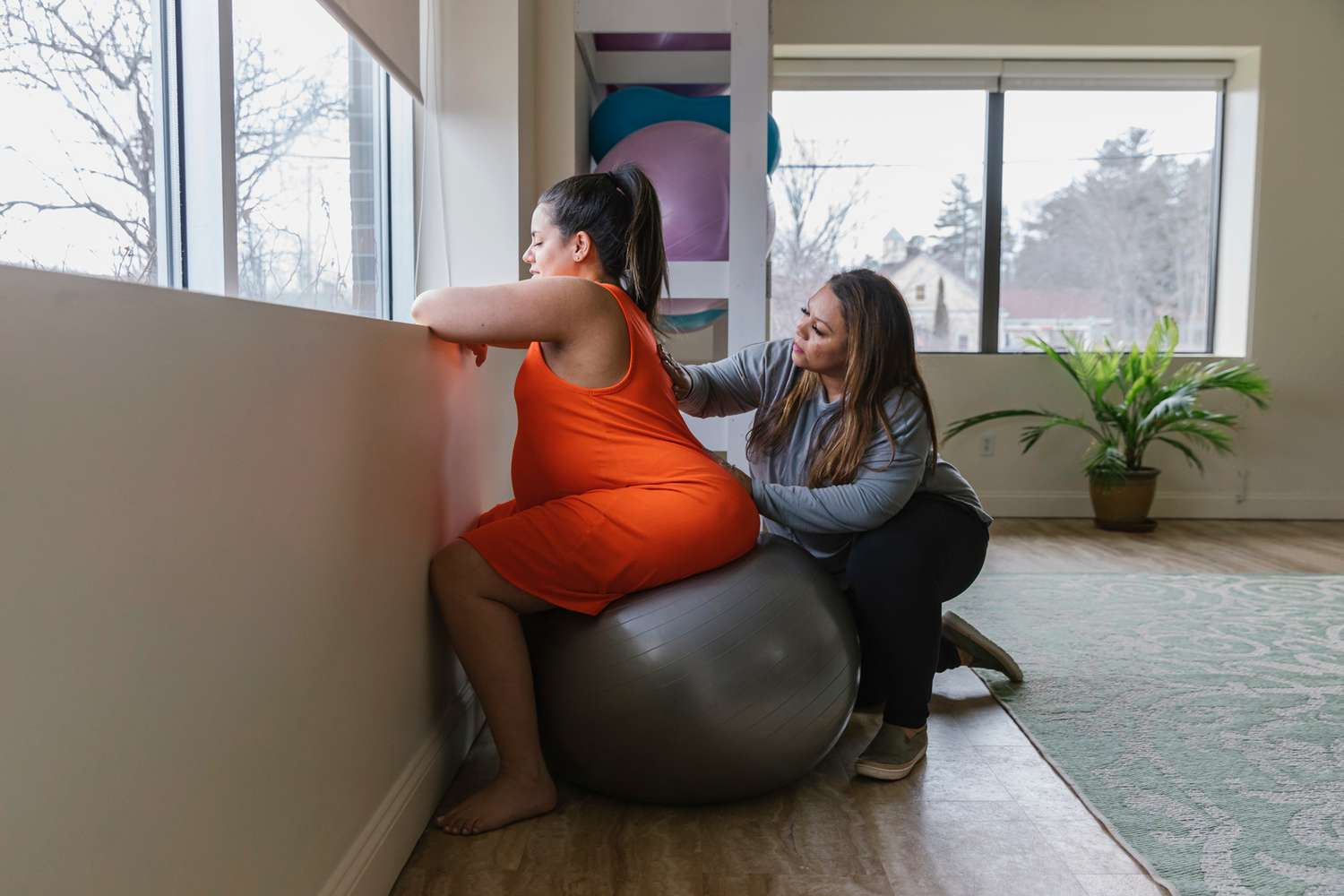 Doula works with pregnant woman on birthing ball