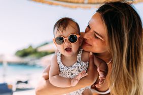 Mother and baby on the beach under an umbrella.