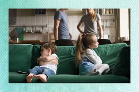 two kids sitting on a green couch while the parents argue in the back ground