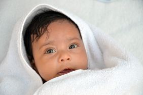 Baby with dark hair and brown eyes swaddled 