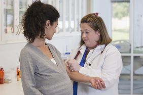 pregnant woman getting vaccine in doctors office