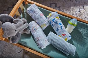 aden + anais Classic 4-Pack Muslin Swaddles placed in a wooden cradle