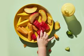 toddler hand grabbing fruit off of a plate