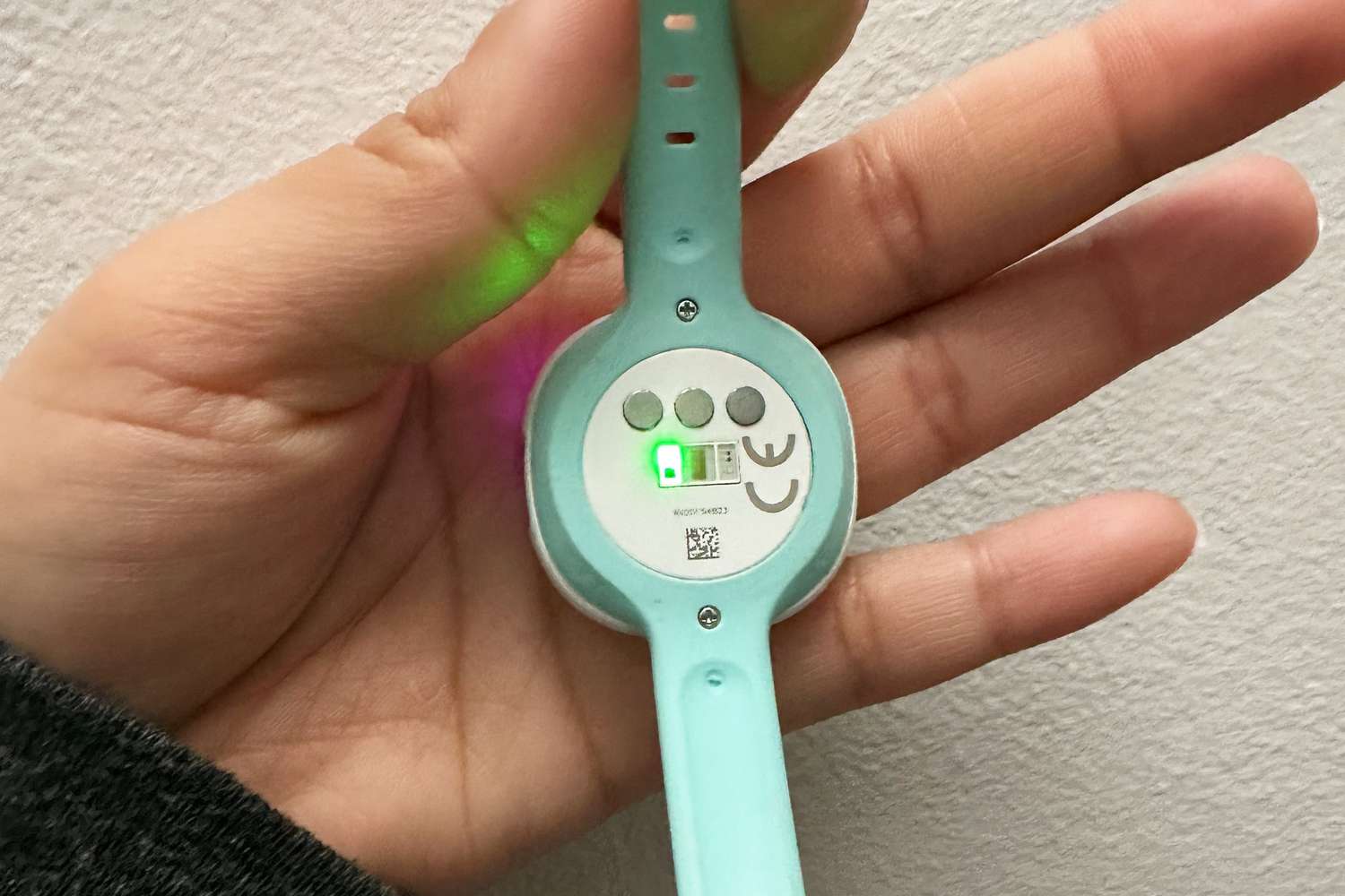 hand holding the Ava Fertility Tracker with green on light showing