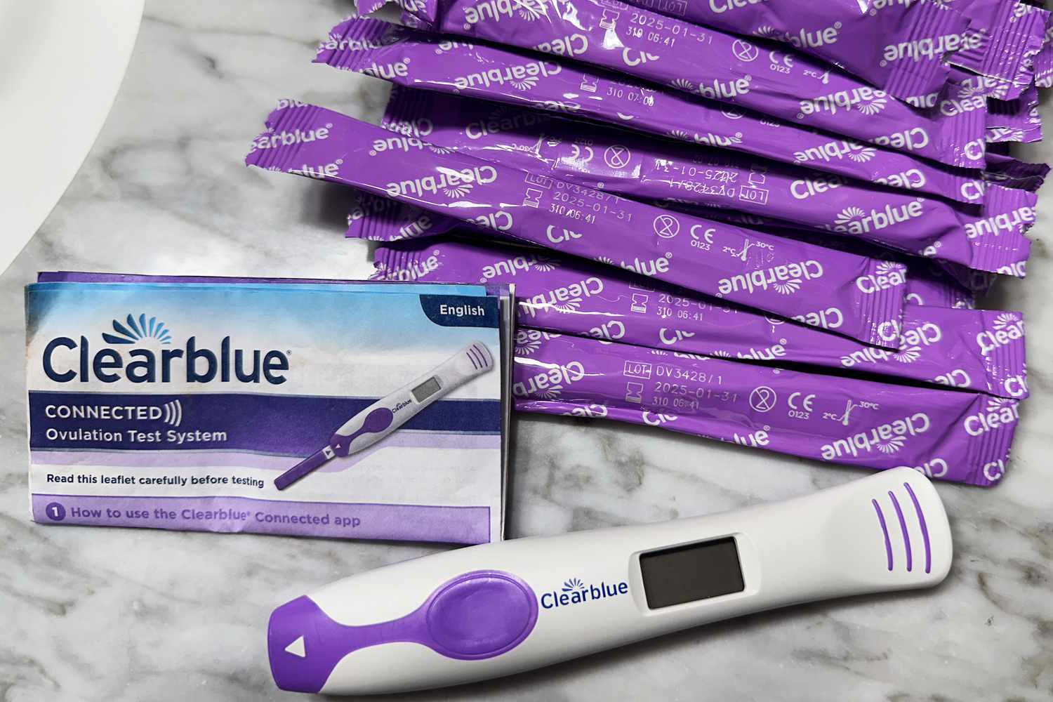 ClearBlue Connected Ovulation Test sticks, manual, and reader on a marble counter