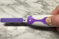 A person holding the ClearBlue Connected Ovulation Test stick and reader