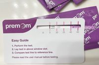 Premom Quantitative Ovulation Test Strip sitting atop its packaging with an instructional card atop that