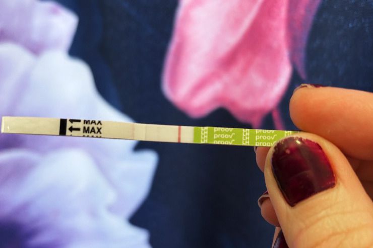 A person holding a test strip from the Proov Predict & Confirm Kit