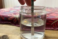 A person dunking a Wondfo Ovulation Test Strip into a jar of water