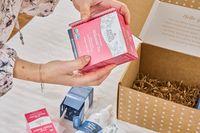 A person removes a box of Earth Mama Milkmaid Tea from the Earth Mama Postpartum Recovery Collection