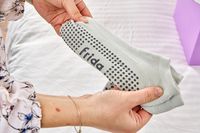 A person holds the Grip Socks from the Frida Mom C-Section Recovery Kit