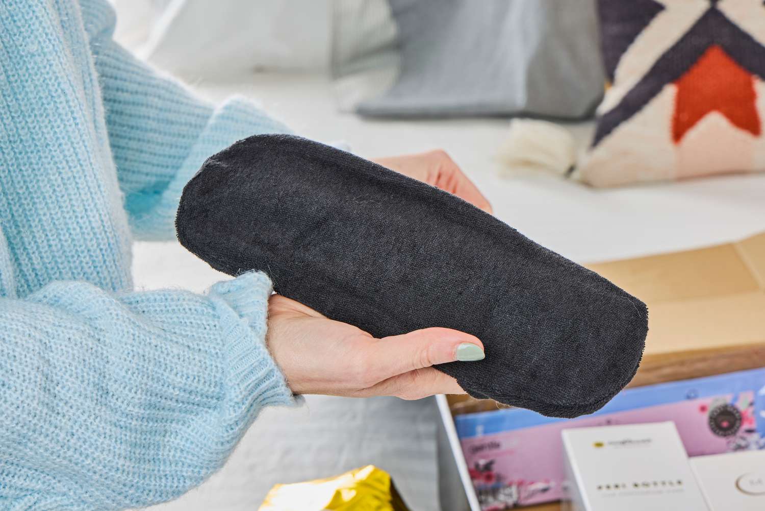 A person holds up the perennial heat/cool pack from the Sunflower Motherhood Deluxe Postpartum Recovery Box