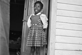 Ruby Bridges, age 6, stands in front of the door of her home