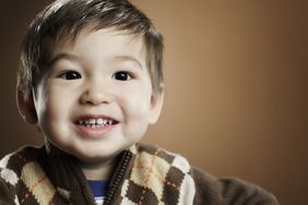 Smiling toddler boy with brown hair wearing an argyle sweater