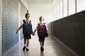 Schoolgirls walking hand in hand at school isle