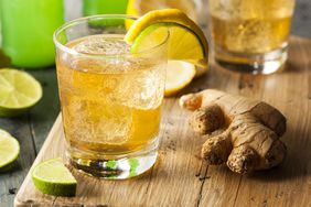 Glass of Ginger Ale Soda and Ginger Root on Wood