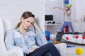 Tired Mother Sitting with Headache Watching Child